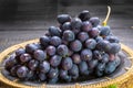 Bunch of ripe blue-black table grape with leaf served on black plate on black wooden background Royalty Free Stock Photo