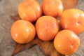 A bunch of ripe crispy persimmons on a yellow leaf