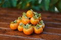 Bunch of ripe orange persimmons lies on a brown wooden table