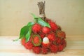 Bunch of Ripe Rambutan Fruits with a Peeled One Isolated on Wooden Table Royalty Free Stock Photo
