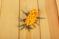 Bunch ripe sea-buckthorn berries on background light wood.