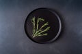 Bunch of rosemary leaves on black plate on black background