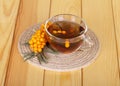 Bunch sea buckthorn and cup tea on background light wood.