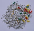 Bunch of shiny silver and gold color safety pins along with colorful push pins Royalty Free Stock Photo