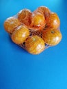 Bunch of tangerines in net bag isolated on blue background