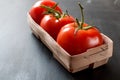 Bunch of fresh red organic tomatoes in rustic basket on grey old kitchen table Royalty Free Stock Photo