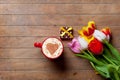 Bunch of tulips, gift and a cup of coffee lying on the table Royalty Free Stock Photo