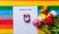 Bunch of tulips, little red clock and sheet of the paper lying o