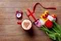 Bunch of tulips, red clock, gift and a cup of coffee lying on th Royalty Free Stock Photo