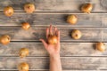 Bunch of unpeeled white onions on faded wooden table, top view. Human hand hold farm vegetables. Organic food or healthy