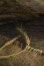 Bunch wheat ears on burlap and wooden background. Royalty Free Stock Photo