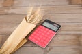 A bunch of wheat ears wrapped in kraft paper and a calculator on the table Royalty Free Stock Photo