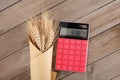A bunch of wheat ears wrapped in kraft paper and a calculator on the table Royalty Free Stock Photo