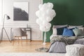 Bunch of balloons in elegant grey and green bedroom interior with king size bed with grey bedding, blue pillows and moss Royalty Free Stock Photo