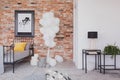 Bunch of white balloons next to single black metal bed with grey bedding and yellow pillow in industrial bedroom interior with