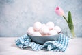 A bunch of white chicken eggs in a blue bowl. Farm product. Nearby are pink tulip. White and blue pastel background. Preparing for Royalty Free Stock Photo