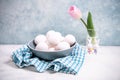 A bunch of white chicken eggs in a blue bowl. Farm product. Nearby are pink tulip. White and blue pastel background. Preparing for Royalty Free Stock Photo