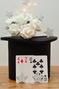 A bunch of white roses in a magicians hat with silver stars and cards