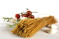 Bunch of whole wheat spaghetti pasta on white wood with some tom Royalty Free Stock Photo