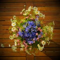 Bunch of wild plants, white camomiles and blue cornflowers on a wooden board .Summer floral composition