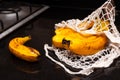 Bunch of yellow bananas in avoska. String bag with sweet organic ripening fruits on black kitchen table background. Close up. Dark