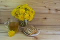 A bunch of yellow dandelions. A glass of tea in a glass mug. Two slices of honey roll with cream. Royalty Free Stock Photo