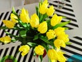 A bunch of yellow fresh tulips stabding in vase on dining table. View from above Royalty Free Stock Photo