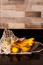 Bunch of yellow overripe bananas in avoska. String bag with sweet organic fruits on black kitchen table background. Close up.