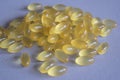 A bunch of yellow translucent vitamins capsules on a gray fabric