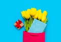 Bunch of yellow tulips and blue envelope in cool shopping bag an