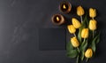 a bunch of yellow tulips next to a candle