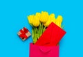 Bunch of yellow tulips and red envelope in cool shopping bag and