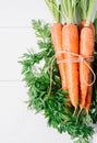 Bunch of young carrots with green tops on white wooden vintage table, healthy food on mock up background top view Royalty Free Stock Photo