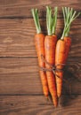 Bunch of young carrots with green tops on wooden vintage table, healthy food on mock up background top view Royalty Free Stock Photo