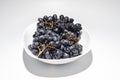 Bunches of blue grapes in a white plate on a white background. Berries, summer harvest, healthy eating Royalty Free Stock Photo