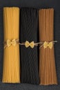 Bunches of different types of Italian spaghetti. Black, brown and yellow spaghetti on gray background Royalty Free Stock Photo
