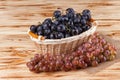Bunches of fresh ripe blue grapes in wicker basket on piece of sackcloth on a wooden textured backdrop. Beautiful background with Royalty Free Stock Photo