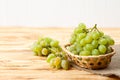 Bunches of fresh ripe green grapes in wicker basket on piece of sackcloth on a wooden textured backdrop. Beautiful background with Royalty Free Stock Photo