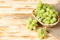 Bunches of fresh ripe green grapes in wicker basket on piece of sackcloth on a wooden textured backdrop. Beautiful background with Royalty Free Stock Photo