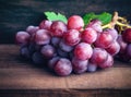 Bunches of fresh ripe red grapes on a wooden textural surface. Ancient style, a beautiful background with a branch of