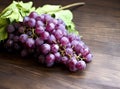 Bunches of fresh ripe red grapes on a wooden textural surface. Ancient style, a beautiful background with a branch of