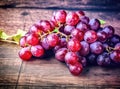 Bunches of fresh ripe red grapes on a wooden textural surface. Ancient style, a beautiful background with a branch of