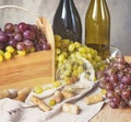 Bunches of grapes, wineglass, bottles and corks on wooden background. Royalty Free Stock Photo