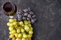 Bunches of ripe green and blue grapes with a glass of red wine, a corkscrew and wine corks on a dark stone background. Top view. Royalty Free Stock Photo