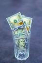 A bundle of American dollars in a glass cup. Glass on a dark background Royalty Free Stock Photo