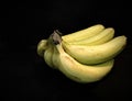 a bundle of bananas sitting on a table with a black background Royalty Free Stock Photo