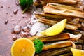 Bundle, bunch of fresh razor clams on ice, dark concrete background, lemon, herbs. Copy space, top view.