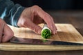 a bundle of chives in a roll ready for slicing, on a wooden cutting board.