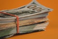 bundle of dollars lying on orange background close up