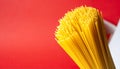 Bundle of uncooked spaghetti pasta with a red background and white element food Royalty Free Stock Photo